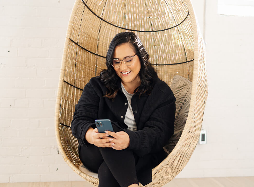 Picture of Jess Sitting in a Boho Chair and Using Her Phone | Real Estate Marketing Trends 2024 | The Listings Lab
